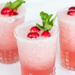 Pretty clear glasses full of Mistletoe Margaritas, topped with fresh mint and cranberries.