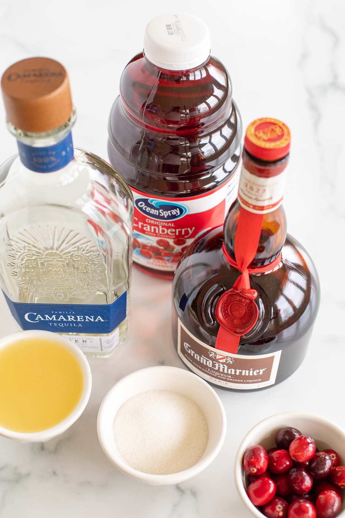 Ingredients for a cranberry margarita laid out on a marble surface