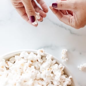 A bowl of popcorn, and a woman's hands showing how to make popcorn garland.