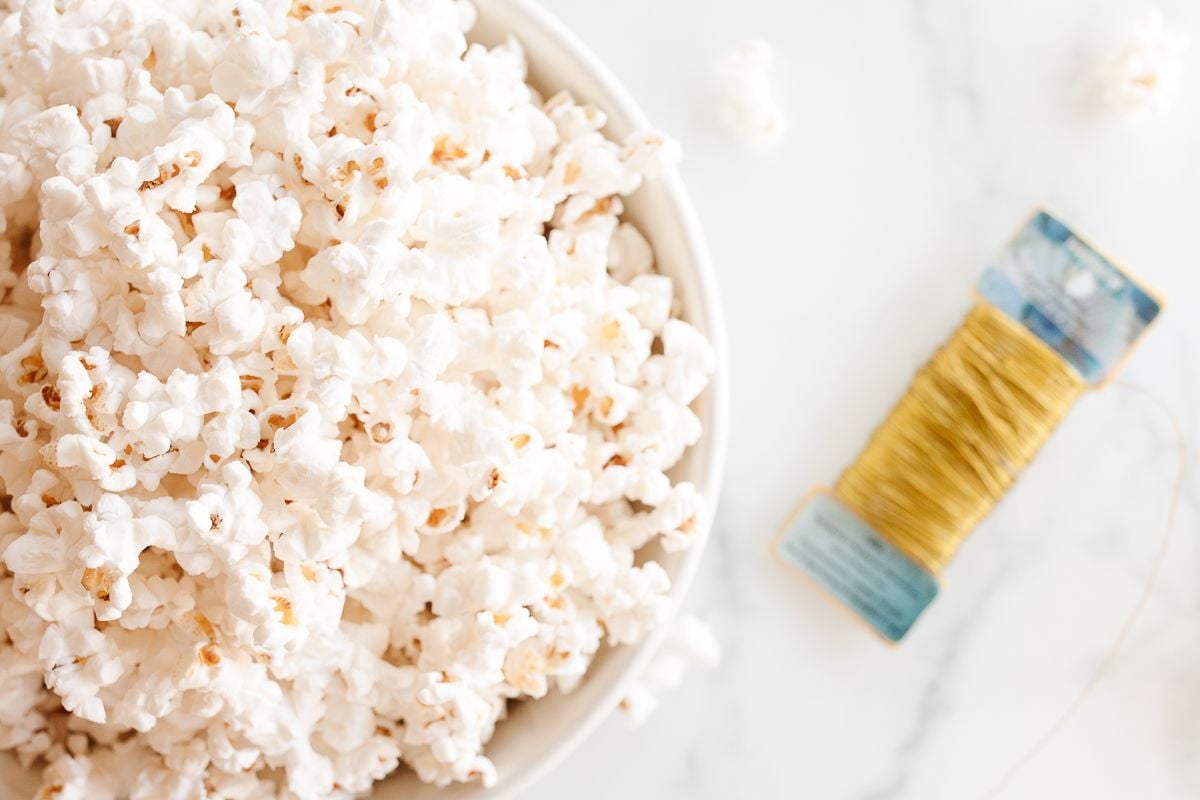 A bowl of popcorn next to a bolt of gold wire.