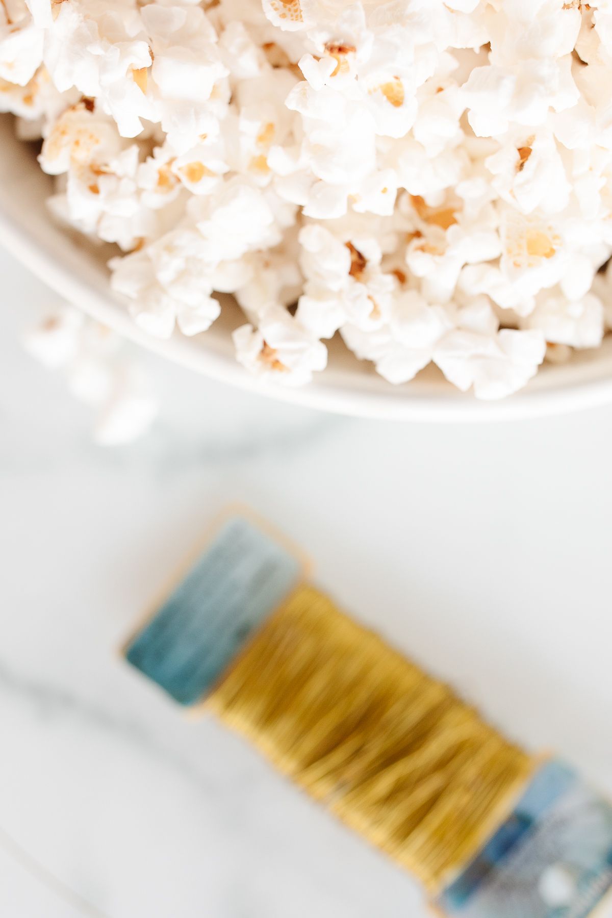 A bowl of popcorn next to a bolt of gold wire.
