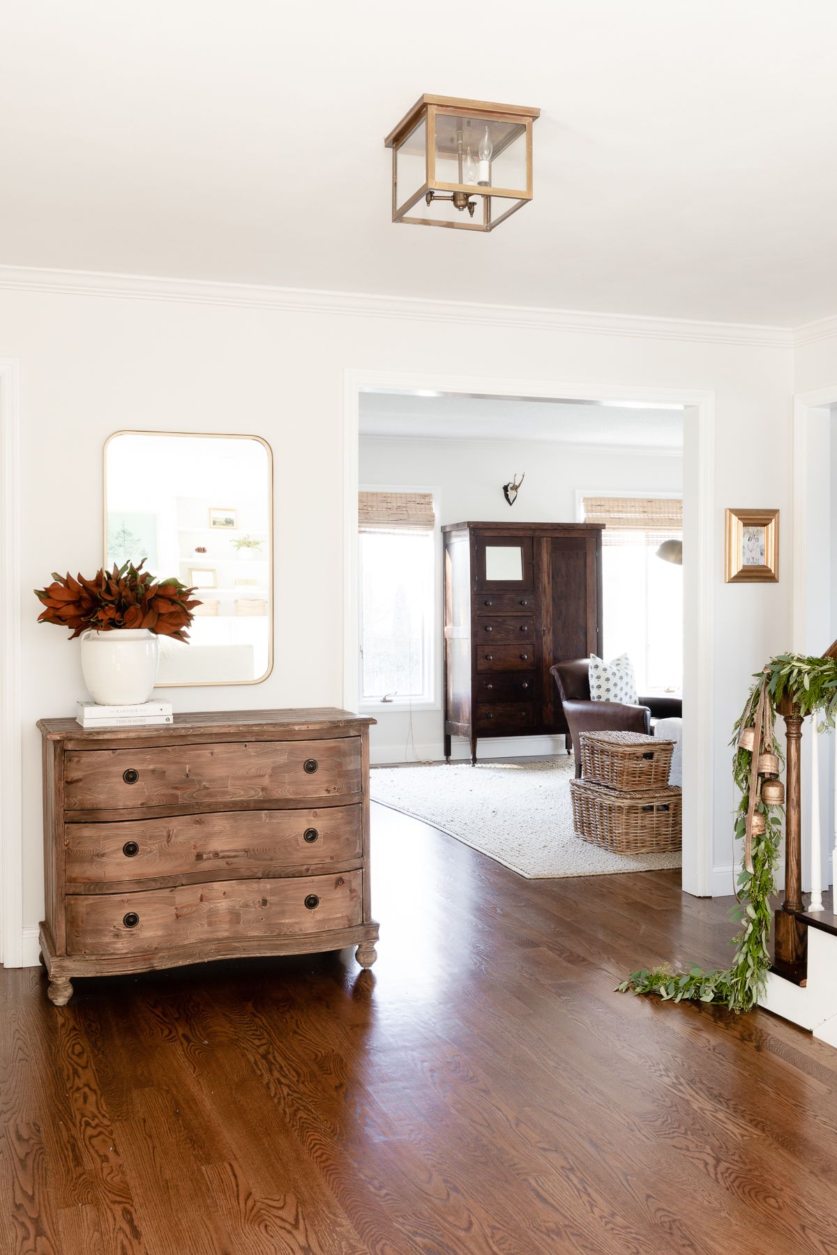 Magnolia branches in a white vase on an entry table