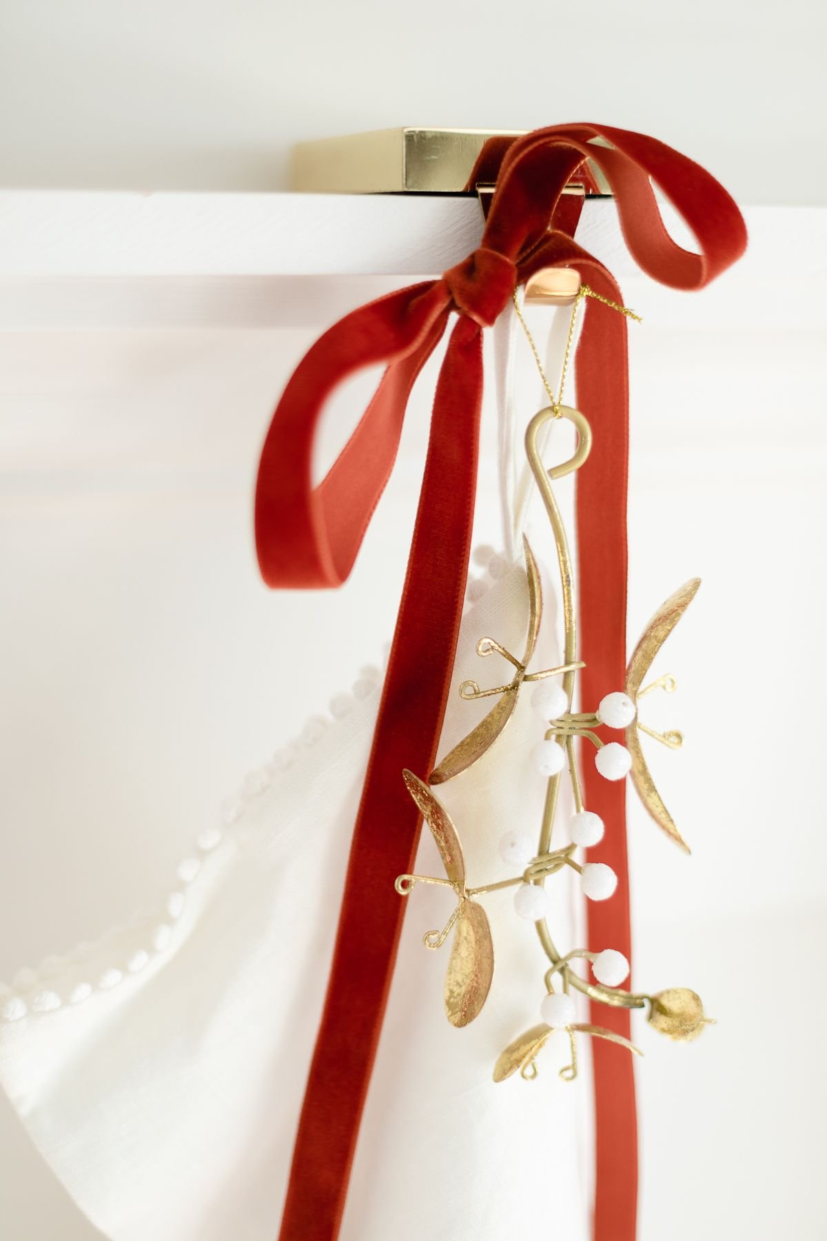 A velvet ribbon and gold mistletoe on a white stocking for traditional Christmas decorating idea