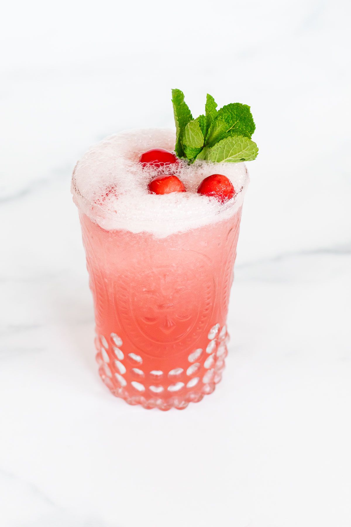 A glass full of a pink toned frozen Mistletoe margarita