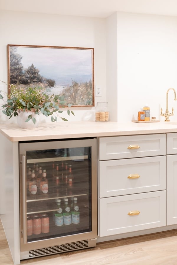 A built in basement bar with a beach scene art piece hanging above