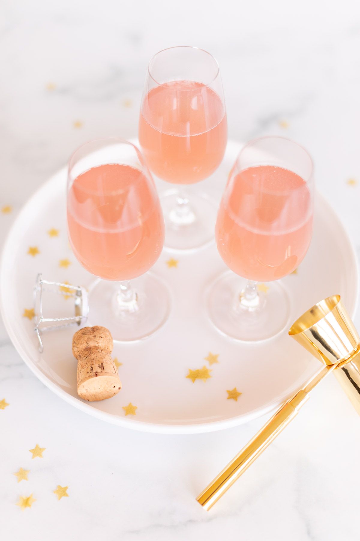 3 glasses of champagne margaritas on a white tray, gold confetti surrounding