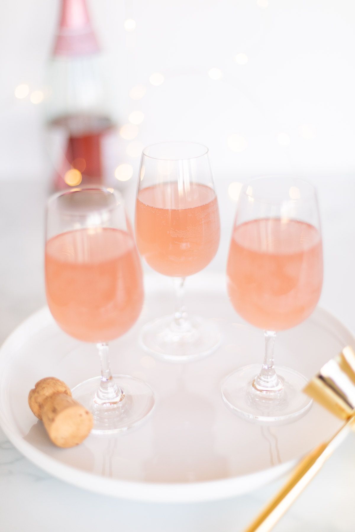 3 glasses of pink champagne margaritas on a white tray with gold confetti surrounding