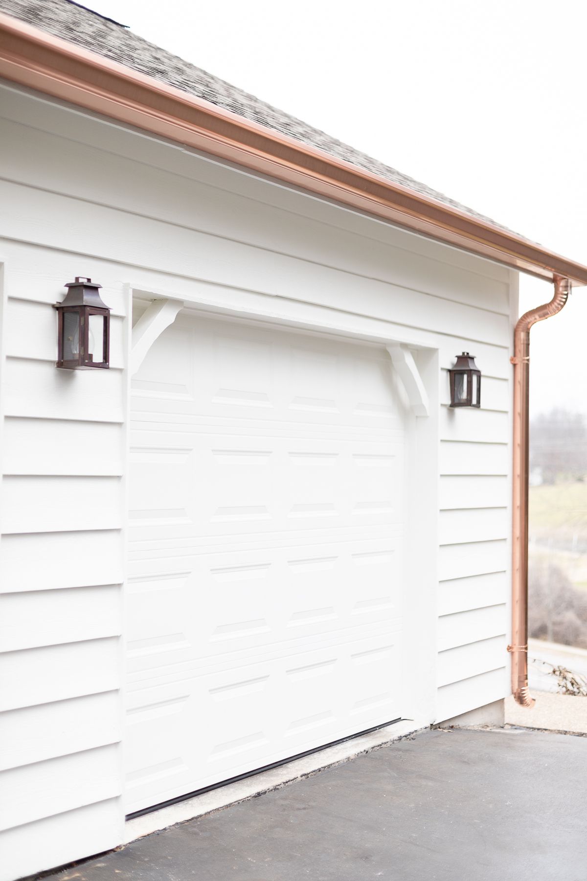 Copper gutters and copper downspouts running over a white exterior garage