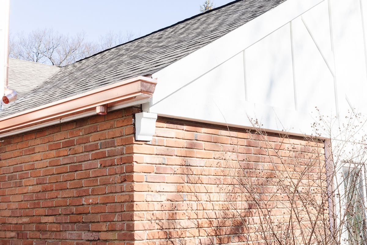 Copper gutters on a white and brick home