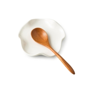 A wooden spoon sits on top of a white plate, adding to the kitchen counter organization.