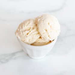 A white bowl on a marble surface, filled with frozen mascarpone ice cream