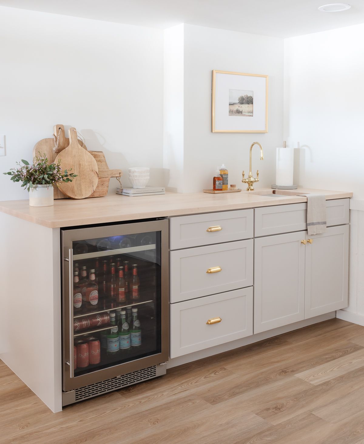 A basement bar with gray cabinets and butcher block countertops