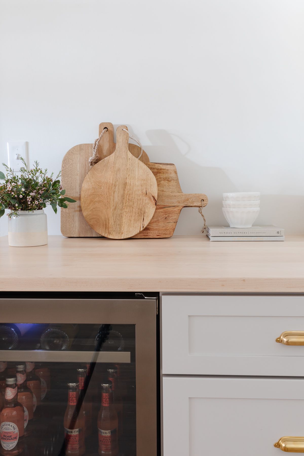 A basement wet bar with a beverage refrigerator and wooden cutting boards