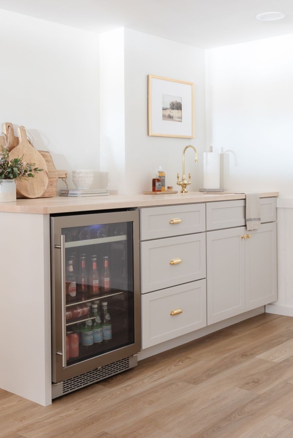 A basement bar with gray cabinets and butcher block countertops