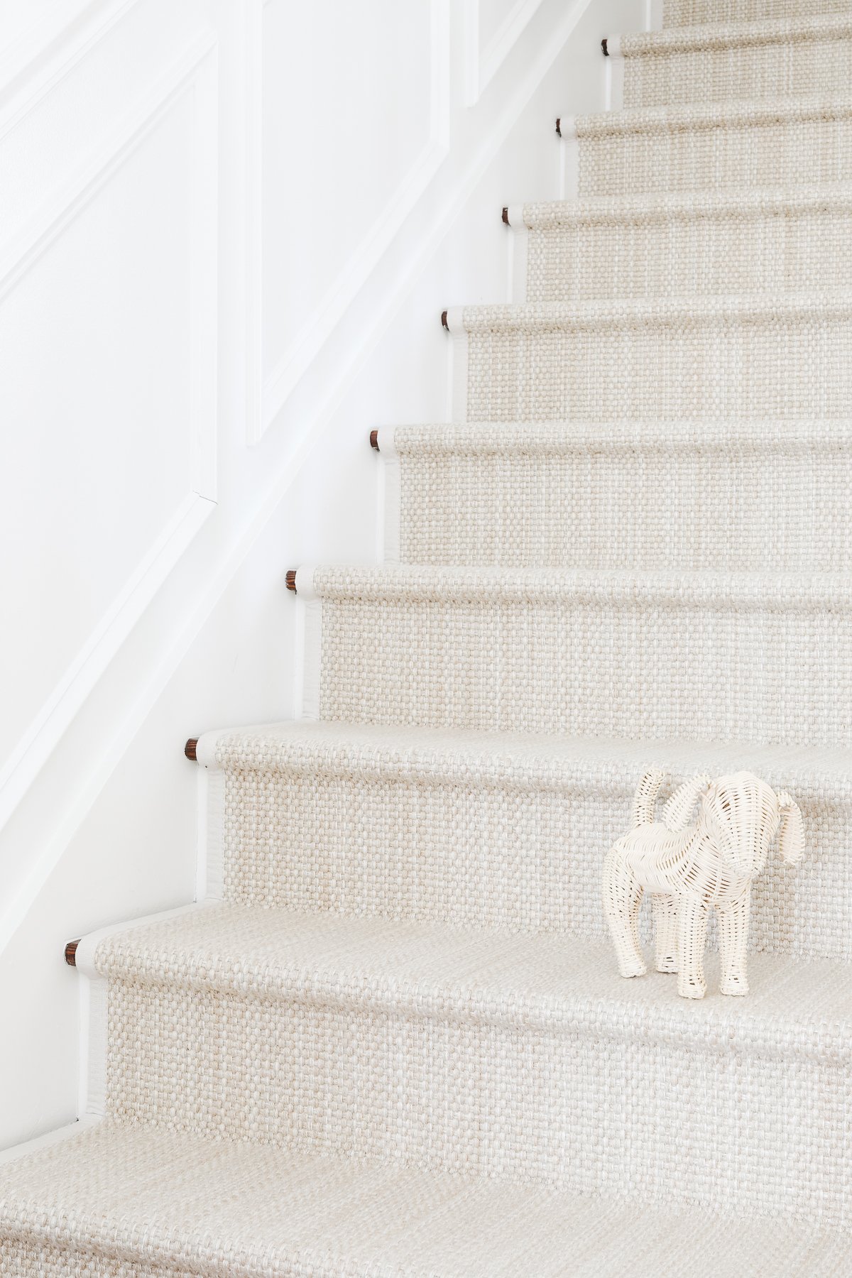 A diy stair runner in a soft neutral color, with a rattan puppy on a step.