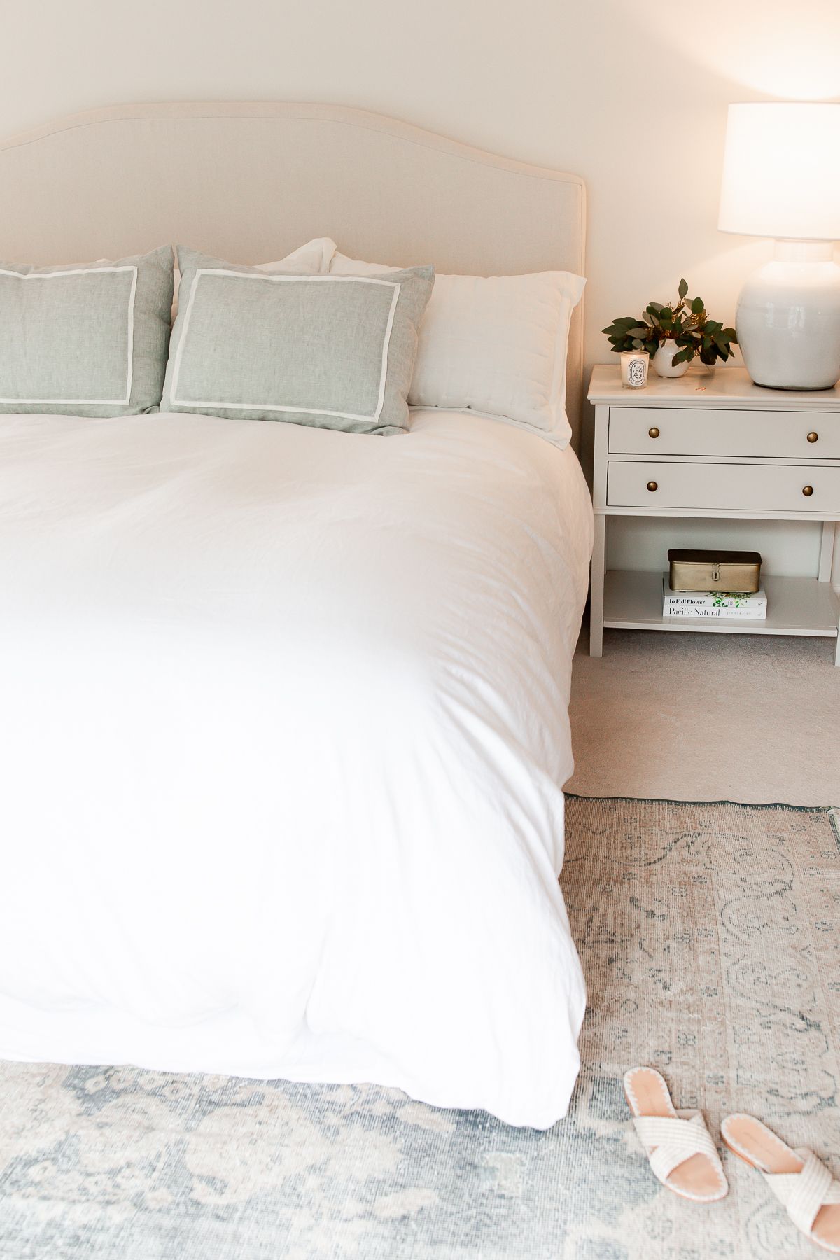 A primary bedroom with white bedding and simple nightstand decorating