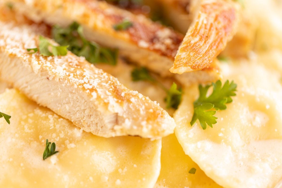 tortellin alfredo with grilled chicken on a white plate.