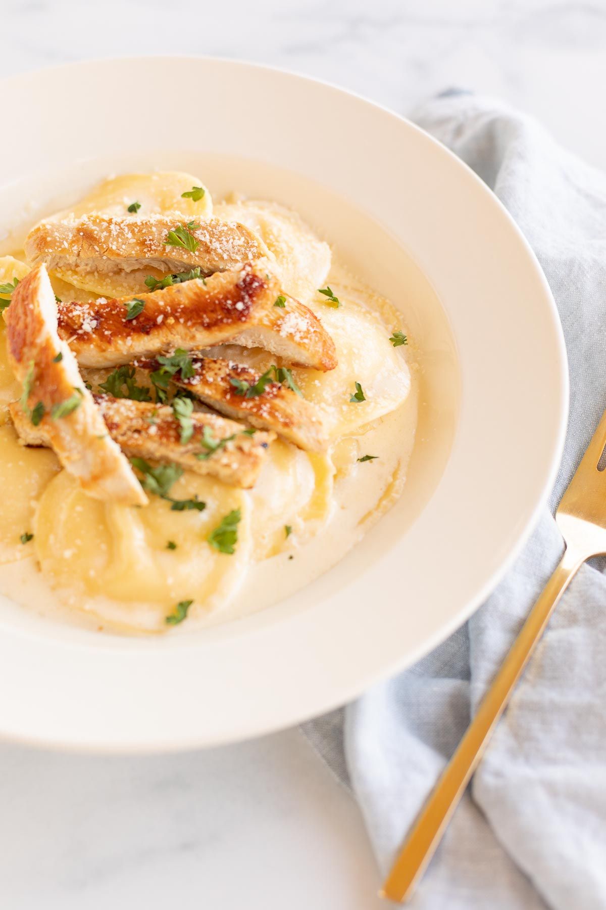 Tortelloni alfredo with grilled chicken on a white plate.