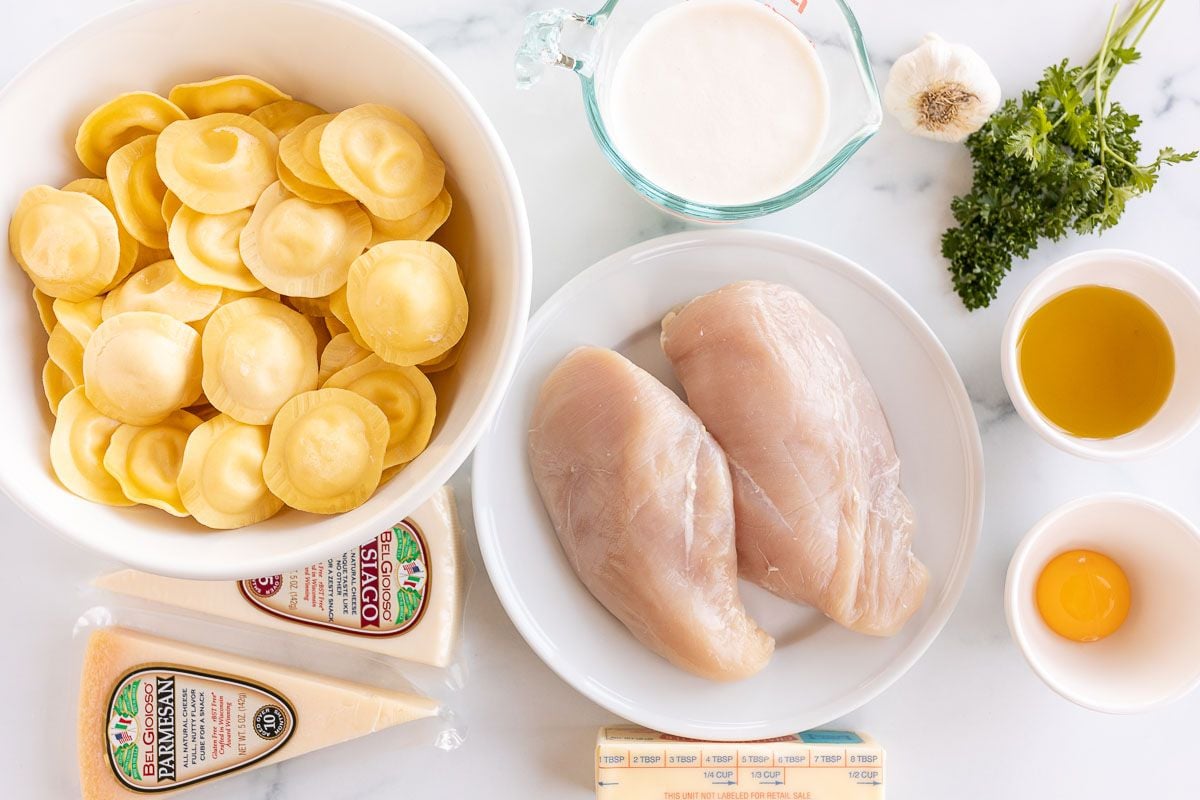 Ingredients for Tortelloni alfredo with grilled chicken laid out on a marble surface