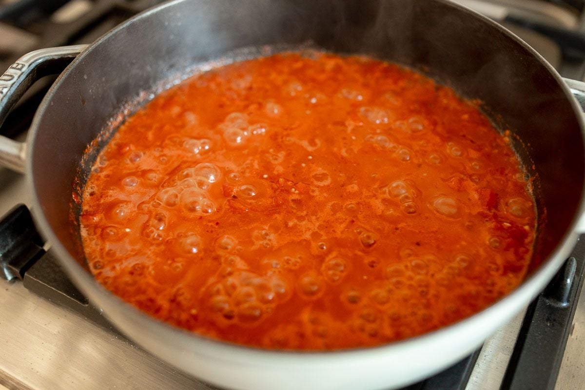 A red sauce simmering in a cast iron pan