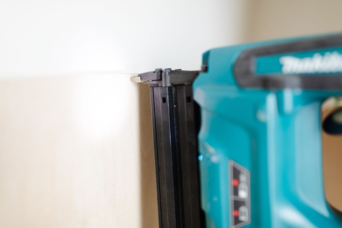 A nail gun nailing a piece of wood mdf to a wall