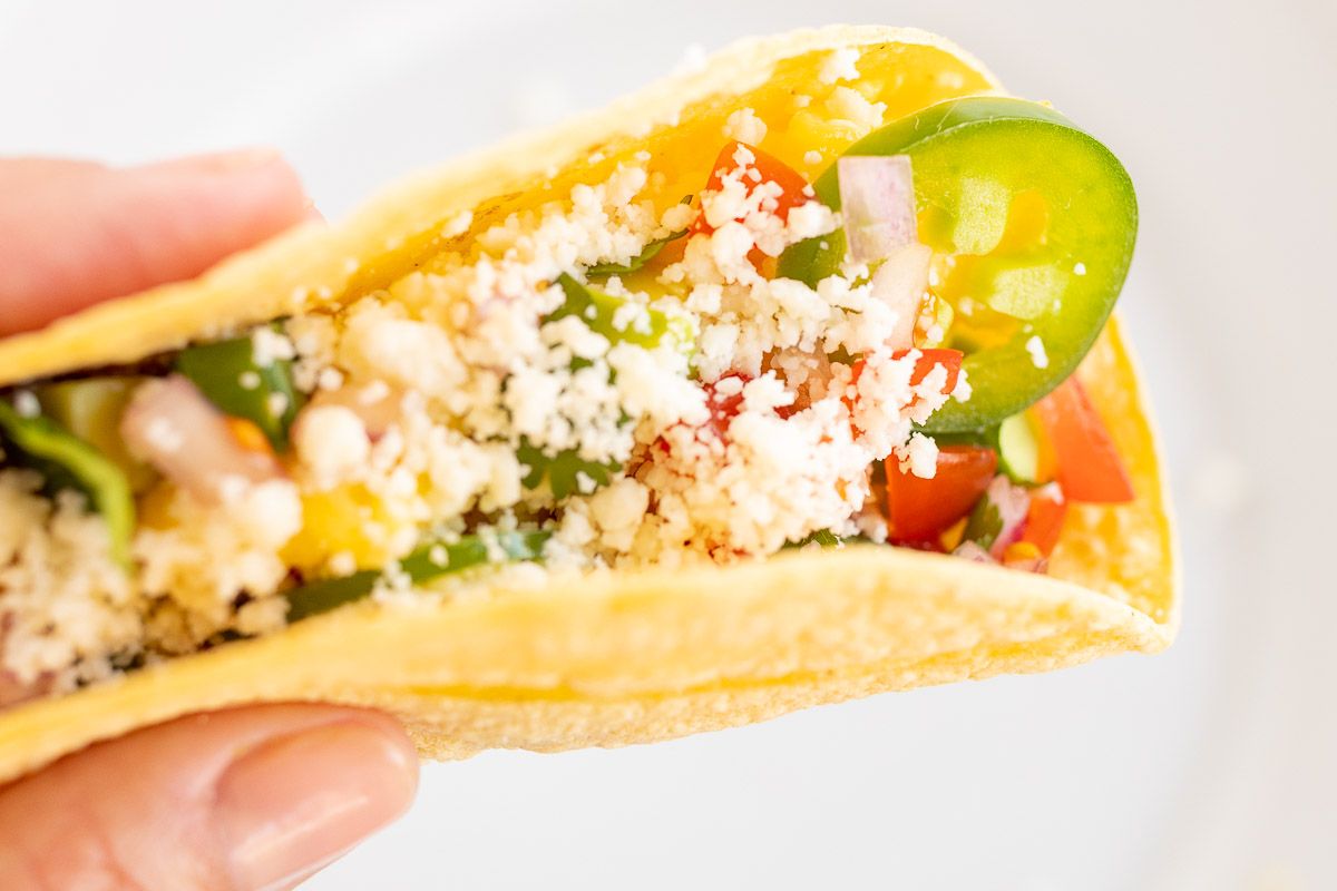 A hand holding a breakfast taco topped with sliced jalapenos