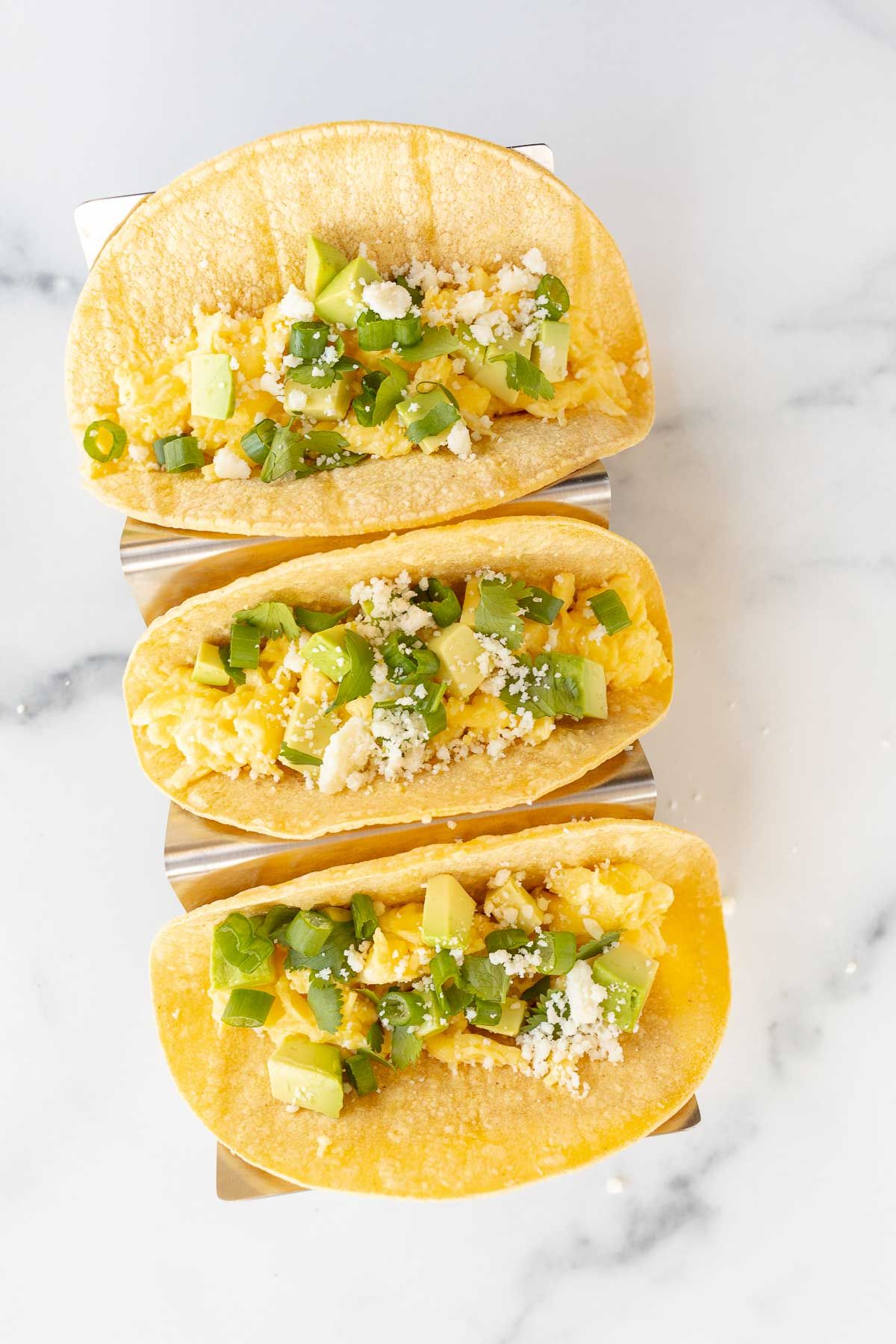 Three breakfast tacos on a marble surface