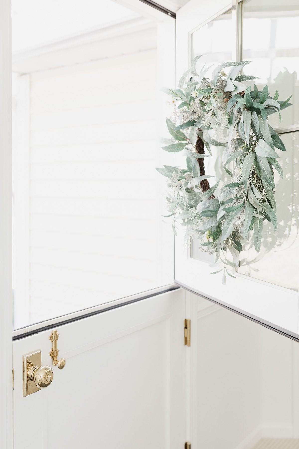 A year round front door wreath in shades of grayish greens on a white dutch door.