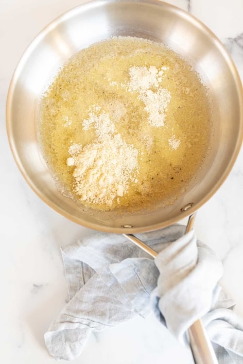 A silver sauce pan full of garlic parmesan sauce