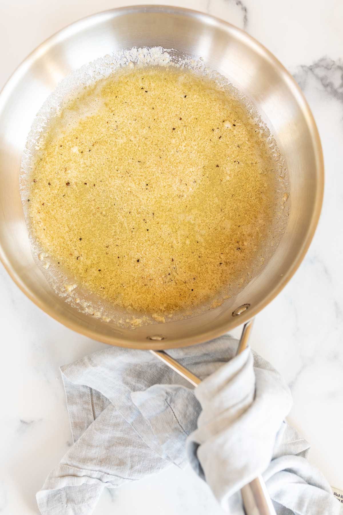 A silver sauce pan full of garlic parmesan sauce