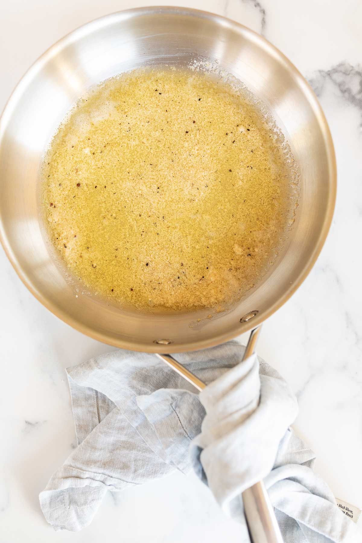 A silver sauce pan full of garlic parmesan sauce