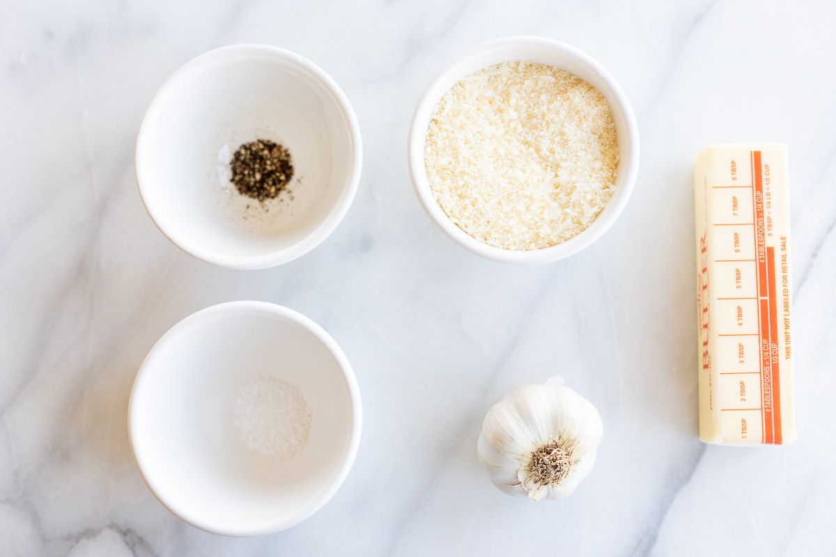 Ingredients for garlic parmesan sauce laid out on a marble surface