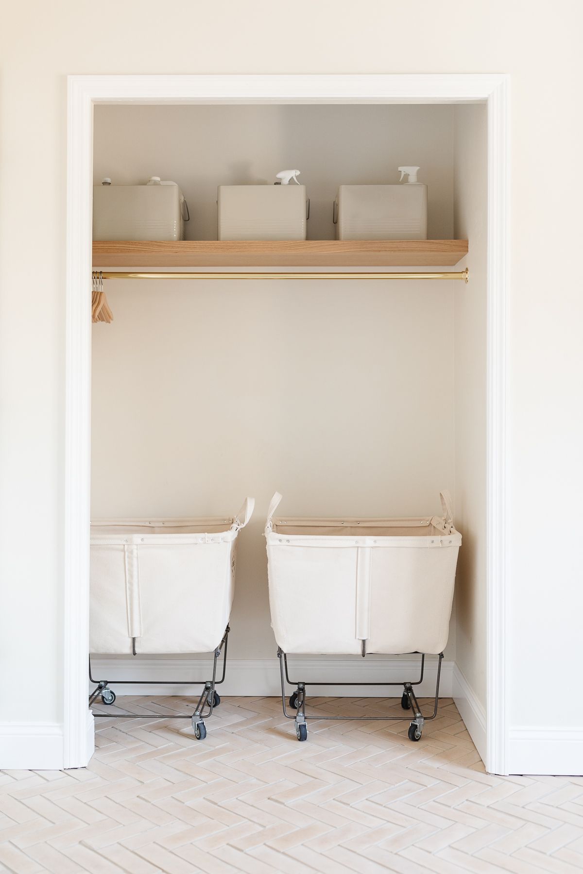 A laundry room with a storage closet and a herringbone tile floor