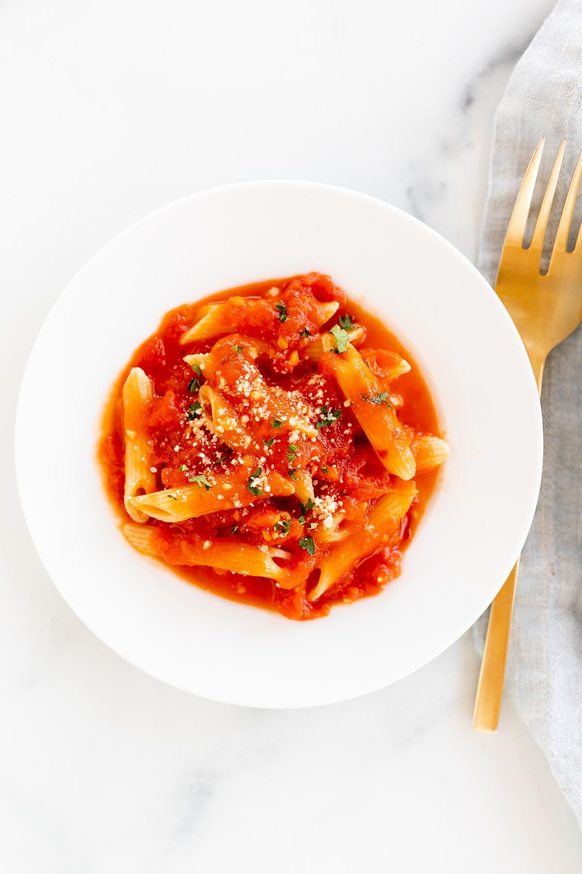 A plate of penne arrabbiata, topped with grated pecorino