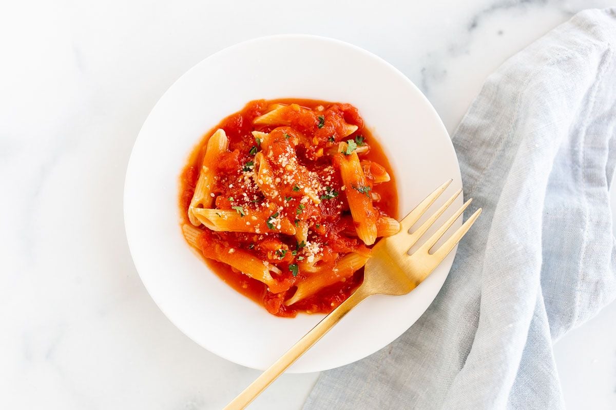 A plate of penne arrabbiata, topped with grated pecorino