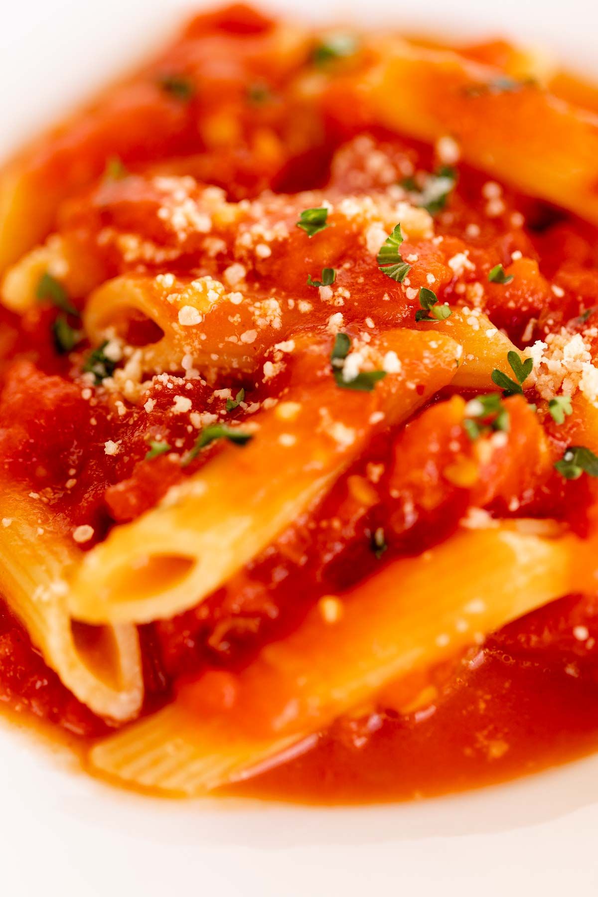 A plate of penne arrabbiata, topped with grated pecorino