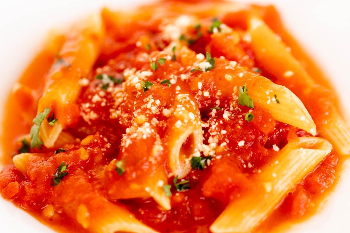 A plate of penne arrabbiata, topped with grated pecorino