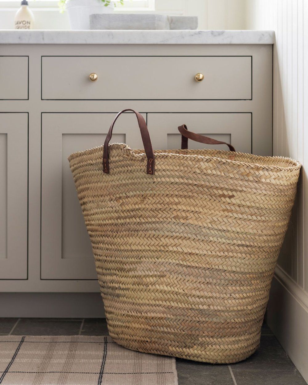 Cabinetry painted in Benjamin Moore Revere Pewter, with a straw tote bag in front of it.