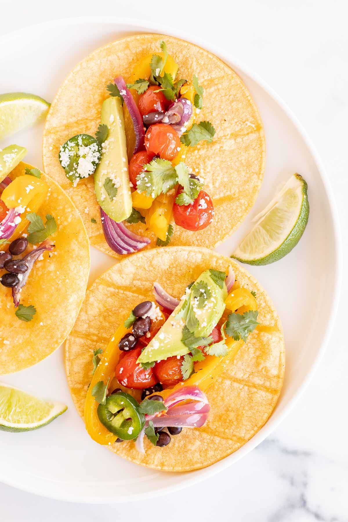 A plate of vegetarian tacos in corn tortillas