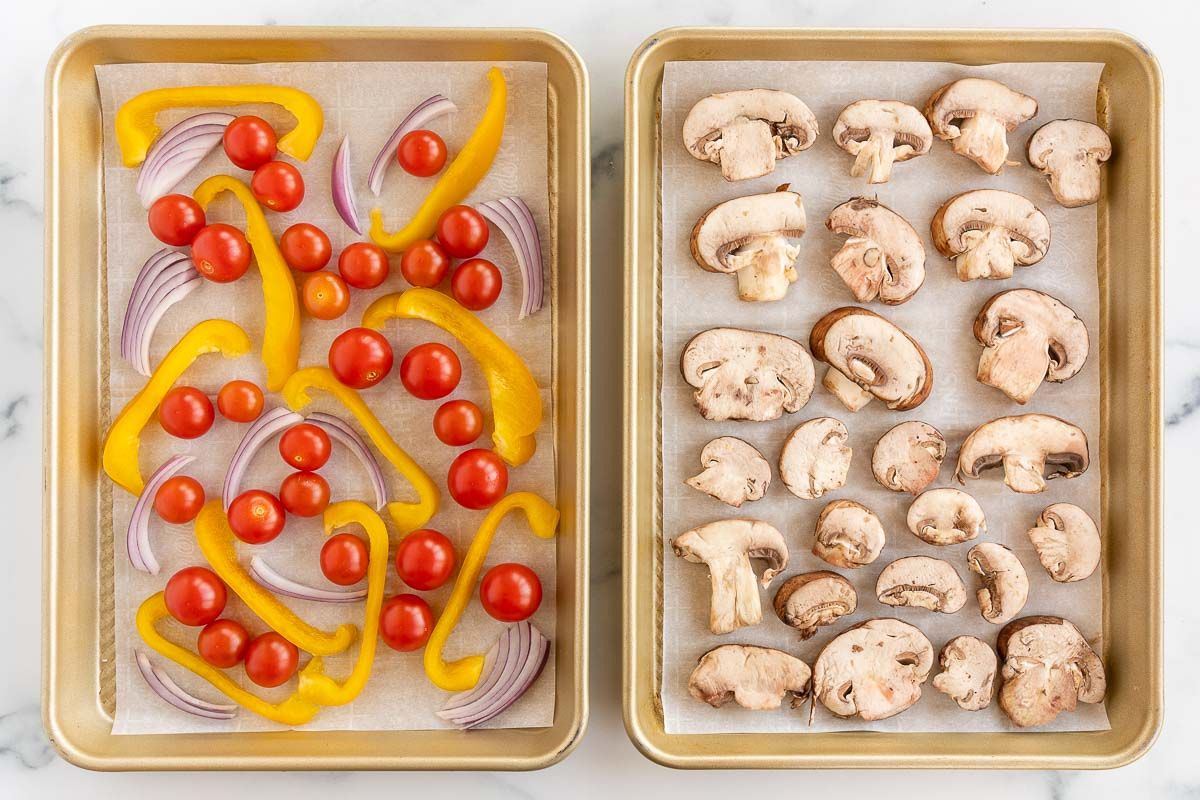 Two gold sheet pans full of sliced veggies prior to roasting