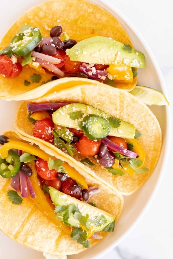 A plate of three veggie tacos in corn tortillas