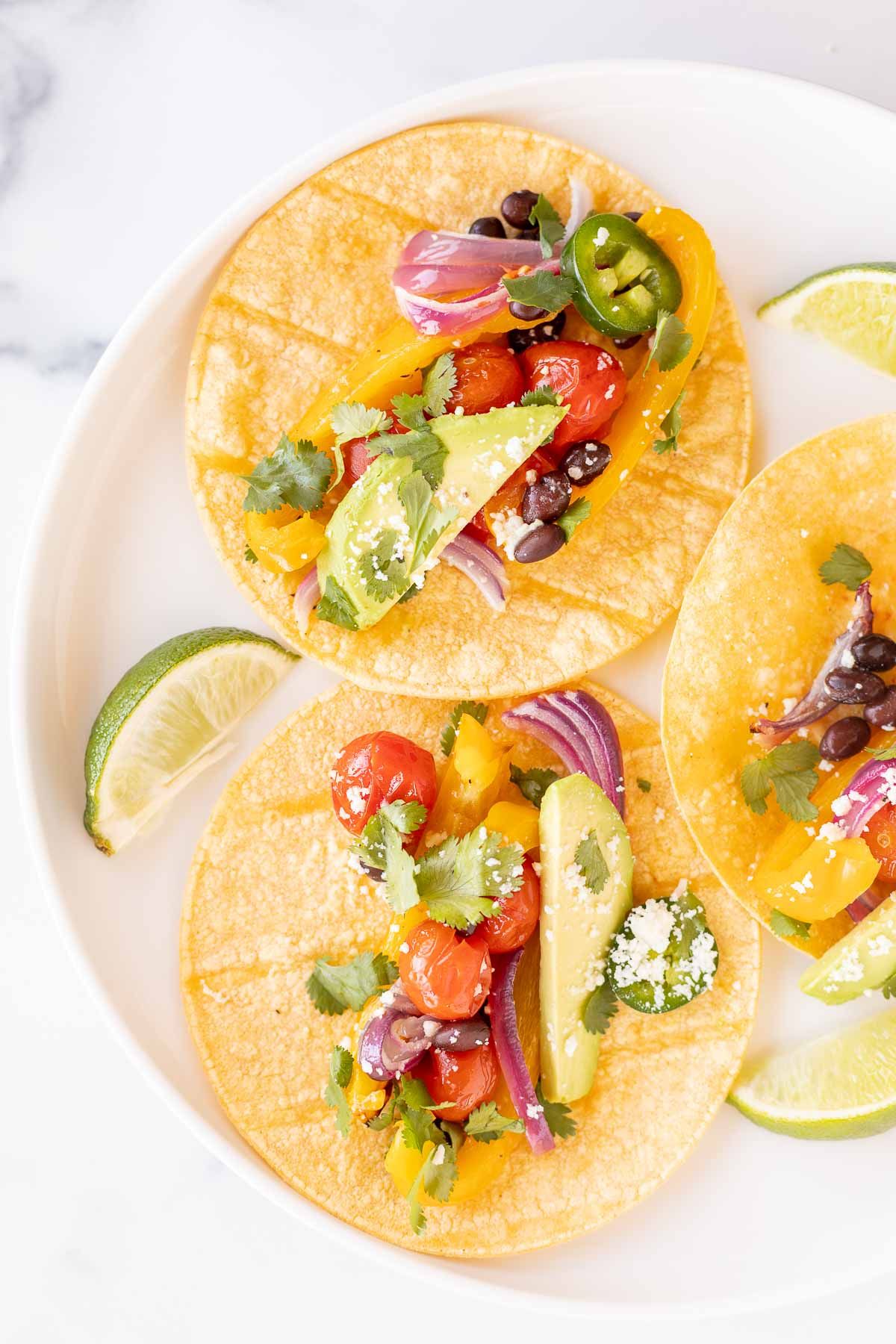 A plate of three veggie tacos in corn tortillas