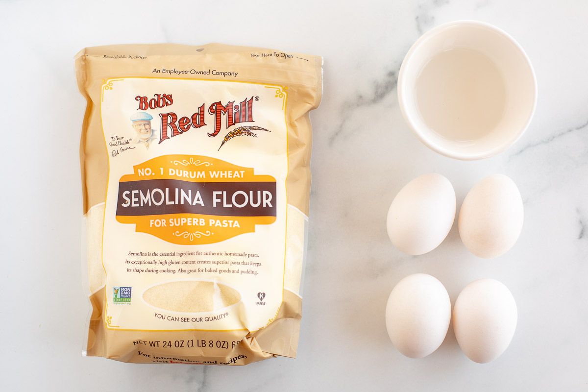 Ingredients for homemade pasta dough laid out on a marble surface.