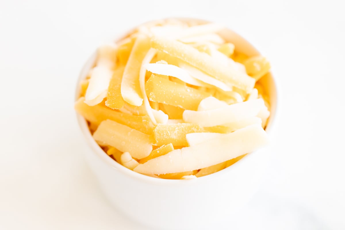 Mexican shredded cheese in a white bowl, perfect for tacos.