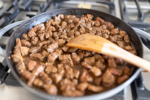 marinated carne asada street taco steak, cooking in a cast iron pan.
