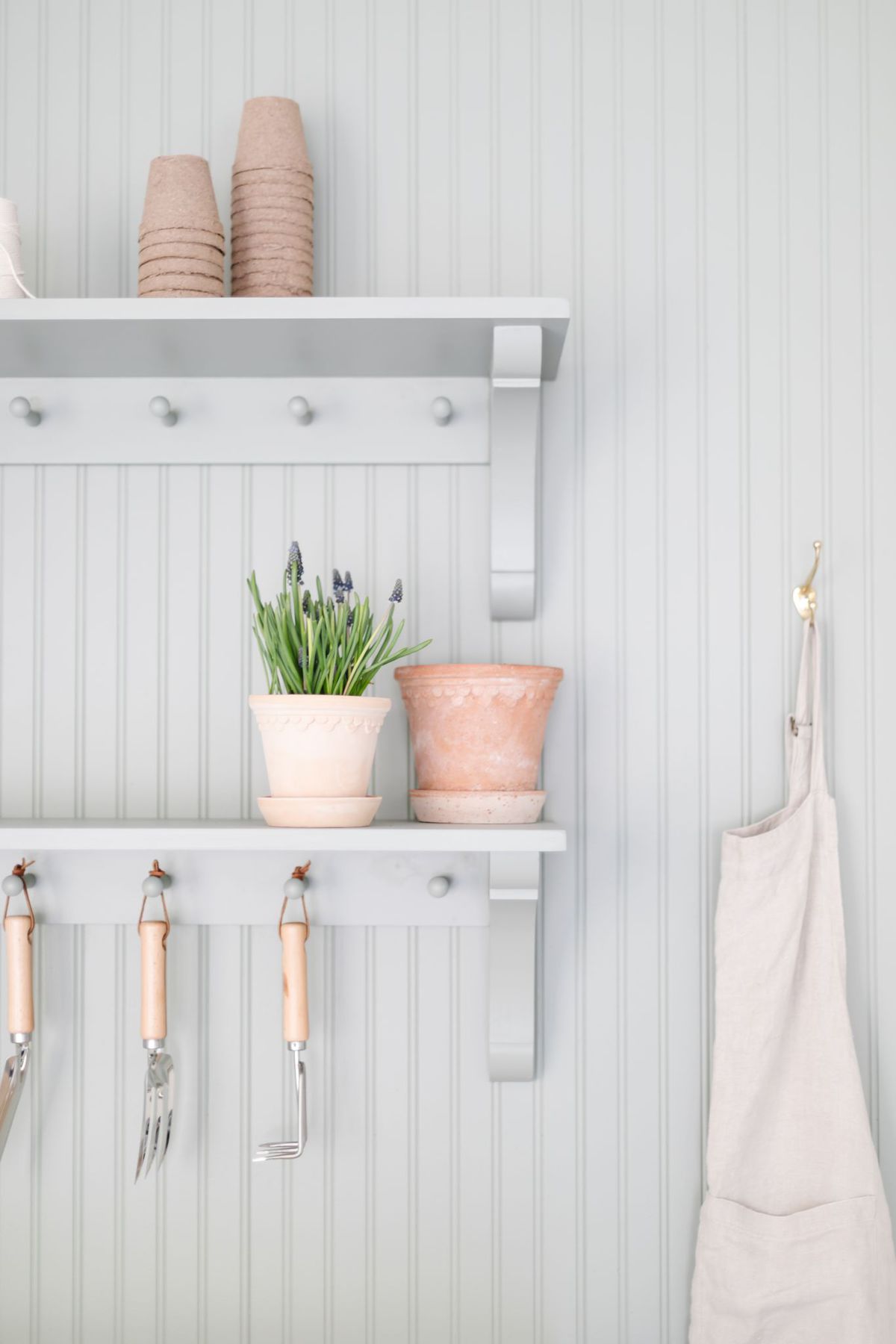 Two hanging peg rails above a potting bench, painted green