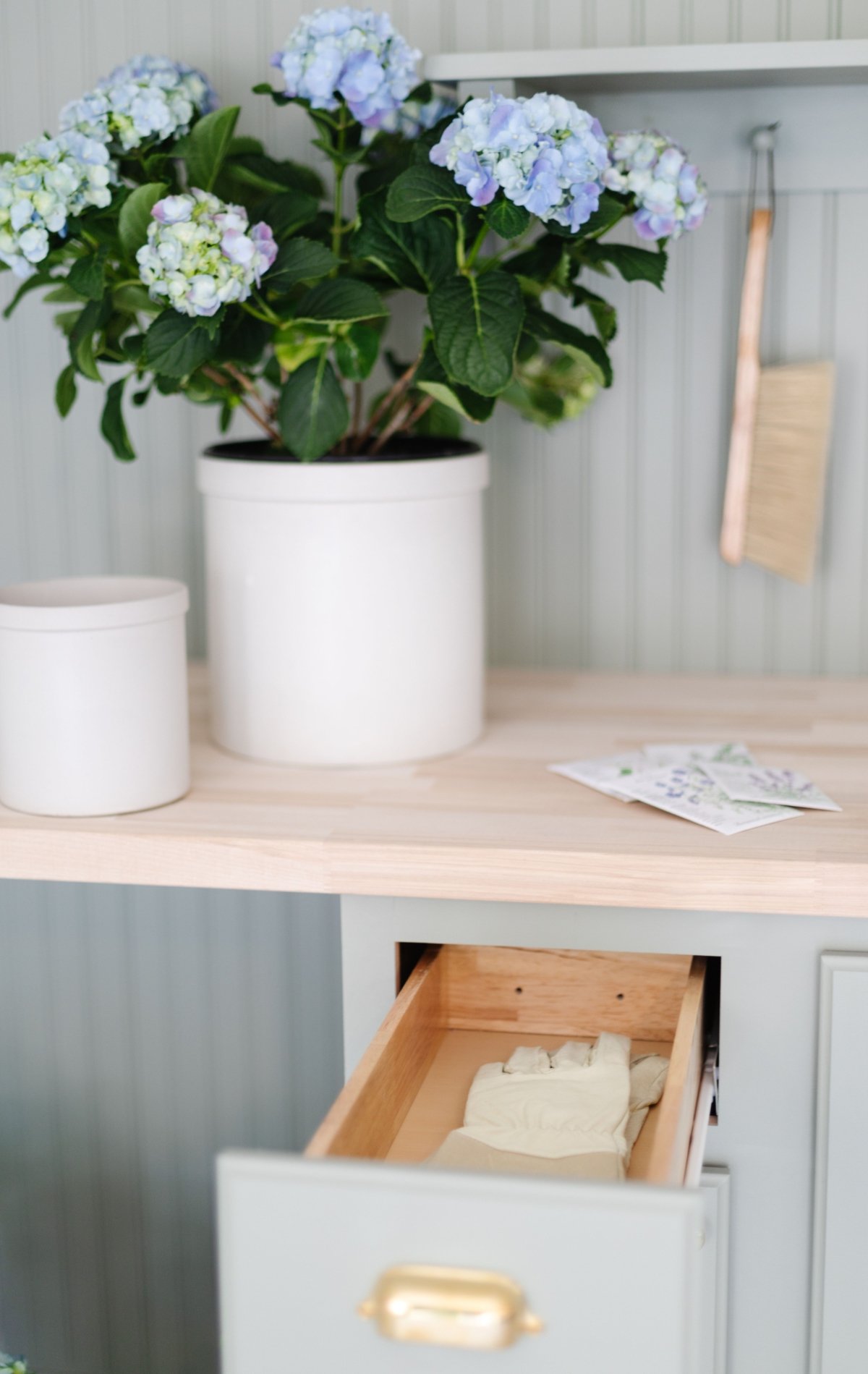 A potting bench with a potted hydrangea, one drawer open