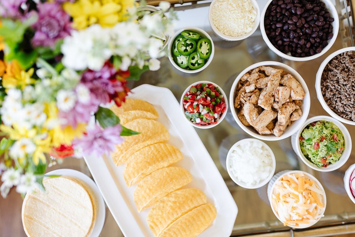 A taco bar display with flowers on a gold bar cart