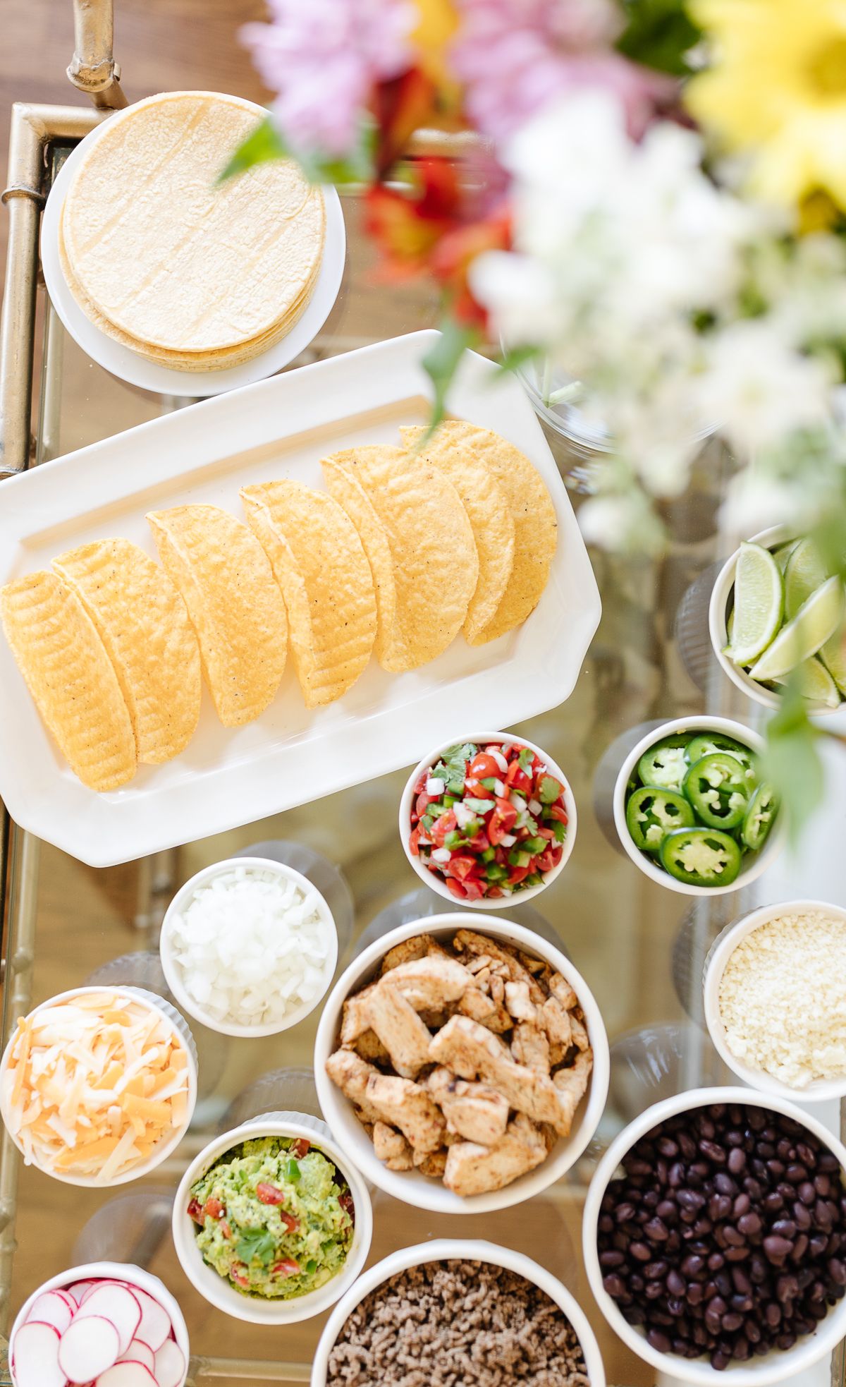 A taco bar display with flowers on a gold bar cart