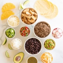 A display of taco toppings on a white marble countertop